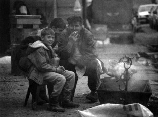 Milenko Milanovic, an ethnic Serb, sits outside a café at the Arizona Market, roasting a pit on a spit with two of the owner's sons.
