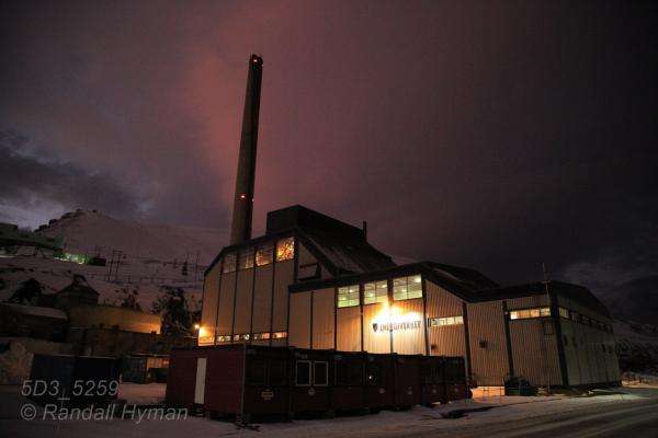 Coal-fired electrical power and heating plant glows amid rosy polar stratus clouds in the polar night of January in Longyearbyen, Svalbard, Norway.
