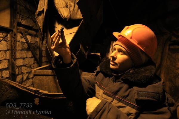 Female mine worker named Natalia studies lump of coal in mine; Barentsburg, Svalbard, Norway.