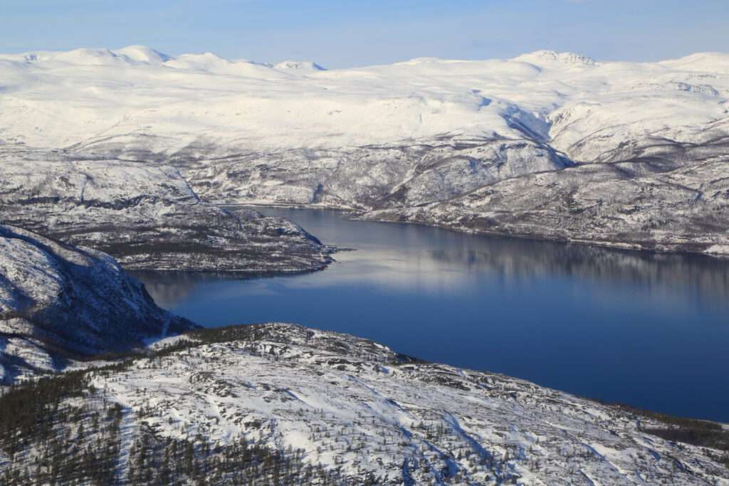 Aerial view in early April of Alta region in northern Finnmark showing distant highland reindeer lands and coastal lands under blanket of snow in Norway’s far north.