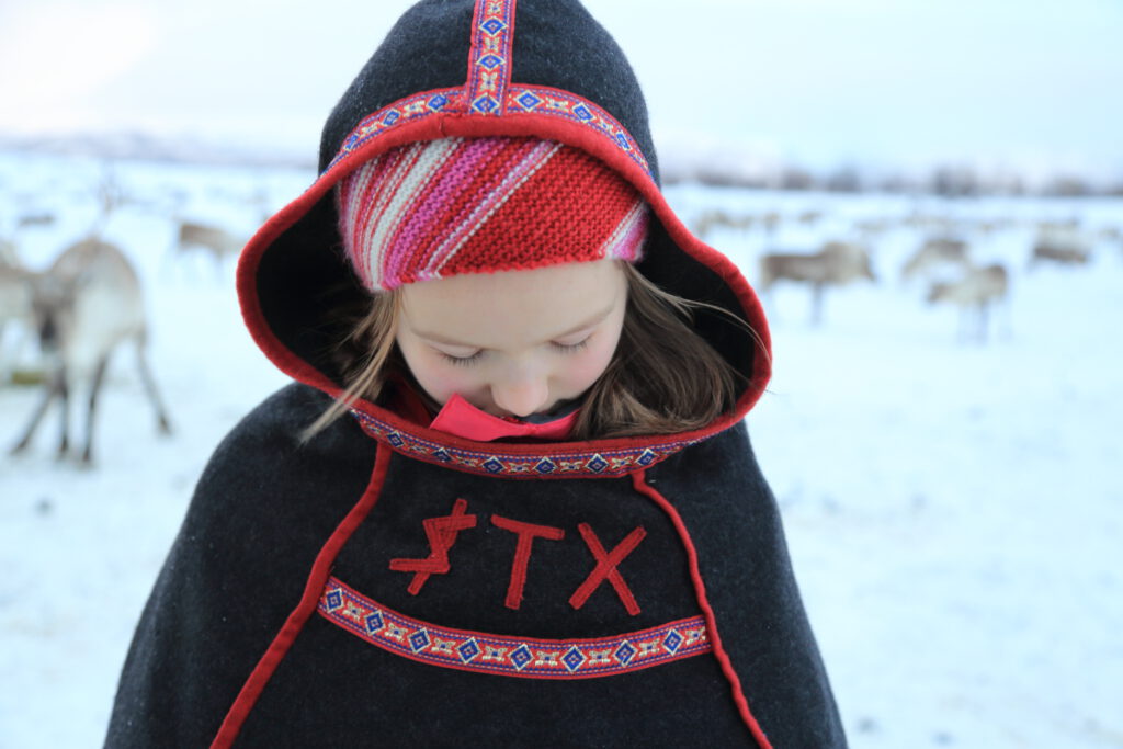 Seven-year-old Sami girl, Eline Oskal, studies her father’s initials emblazoned on his poncho which he put on her to keep her warm while herding reindeer near Tromsø in January 2015.