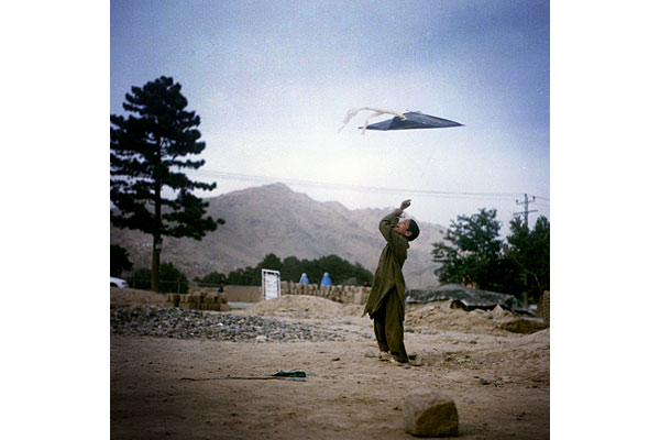 A child living in a displacement camp tries to fly his homemade kite.