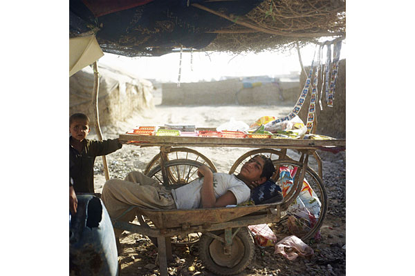 A boy sells small food items and phone cards at his makeshift kiosk.