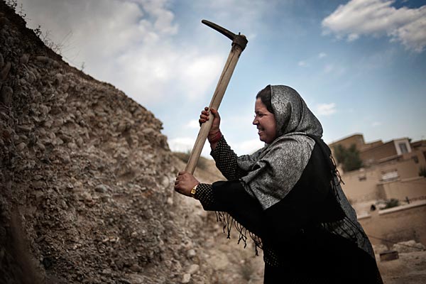 Aneesa, a widow, collects dirt from the hill to make bricks to add a room to her home. Afghan forces have a checkpoint on the hill in order to protect the widows who live there.