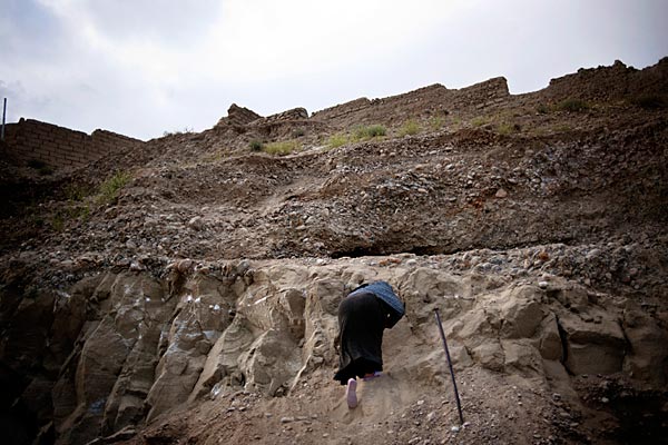Aneesa, a widow, collects dirt from the hill to make bricks and build her home. Her husband died in the late 1990s in fighting in southern Afghanistan.