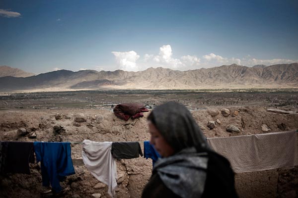 Aneesa, a widow, hangs clothes on her home on a steep hill in Kabul, Afghanistan, June 2011.