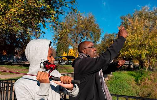 Timothy Poole, founder of Hooked on Fishing not on Violence, shows Brandon Clay Jr., 14, how to cast a line while fishing at Southside Park in November. Poole’s criminal record – erased in 2019 through an expungement process with Legal Services of Northern California – could have barred him from working with children in schools. Lezlie Sterling
