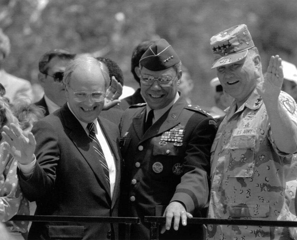 Secretary of Defense Dick Cheney, left, Joint Chiefs Chairman Colin Powell, center, and Desert Storm Commander Gen. H. Norman Schwarzkopf wave from the reviewing stand after they led a ticker tape parade through the streets of New York, June 10, 1991. (AP Photo/Amy Sancetta)