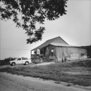 Live–at a Mississippi Juke Joint Po’ Monkey’s place, located amid cotton fields two miles down a dirt road outside Merigold, MS, is perhaps one of the last old-style country jukes in the Delta. It’s been operated by tractor driver Willie “Po’ Monkey” Seeberry for more than 30 years in a turn-of-the-century sharecropper’s shack where Seeberry lives. The juke packs in customers every Thursday night to dance, drink beer, and eat fish, ribs and pork chop sandwiches prepared by his ex-sister-in-law, Irene Johnson. Just as in the boom days of the Delta, the shack is owned by Seeberry’s white employer who allows him to run the club out of his home for extra money and to provide a social outlet for locals. Po’ Monkeys Lounge draws in whites and blacks throughout the Delta who enjoy partying in the country, listening to good blues and eating good food.