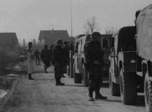 U.S. Army soldiers wait along a village road last fall after other American troops threw up a roadblock. They discovered that Muslim homes under reconstruction in the zone-of-separation near Brcko had been rigged with dynamite by Serbs opposed to Muslim resettlement in the Serb Republic of Bosnia.