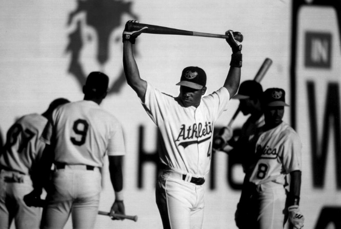 Miguel Tejada, of the Class A Modesto Athletics, stretches before a game, his teammates in the background. An amazing defensive shortstop, Tejada also shows great power at the plate. It is early in the 1996 season and he is showing the confidence of a player on the way up.