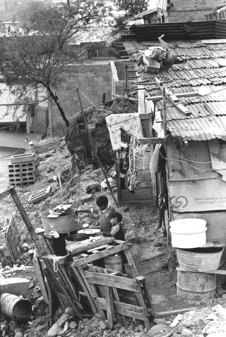 A nogales, Sonora, house made of discarded cardboard, wooden pallets and tin is home to two boys who are washing their hands in barrels once used to store industrial chemicals. Such a scene is common along the border.