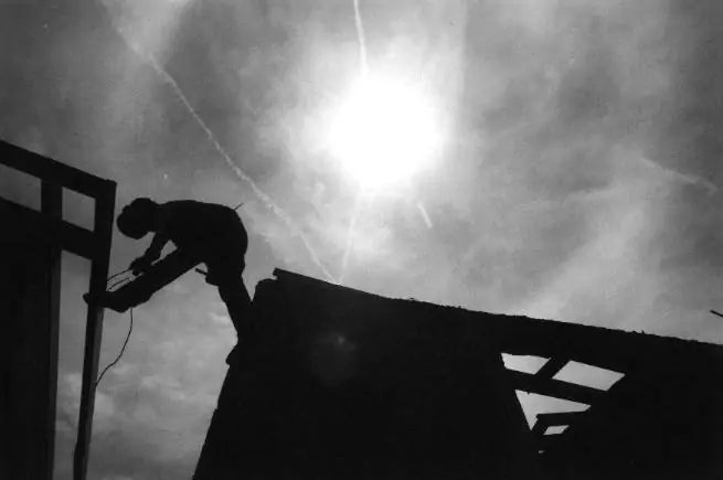 A welder pieces together sections of roof trusses on one of the 250 homes currently under construction in the San Carlos housing project.