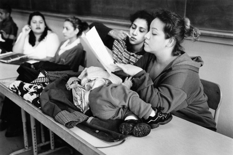 Mirna and a classmate look over a class paper, while Nathan sleeps on her desk. Photo by APF Fellow Donna Decesare