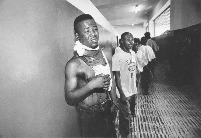At the public hospital a young man waits to see the doctor after a gang member tried to slit his throat with a machete.