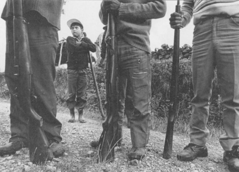 Baltazar, age 11, leans on his hoe behind a group of civil patrollers outside of Nebaj, Guatemala.