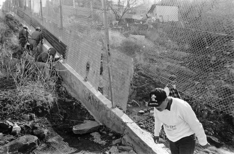 Border Patrol agents repair holes in the fence between the twin cities of Nogales, Arizona, and Nogales, Sonora, while a man steps into the U.S. The steel wall has existed since 1994.