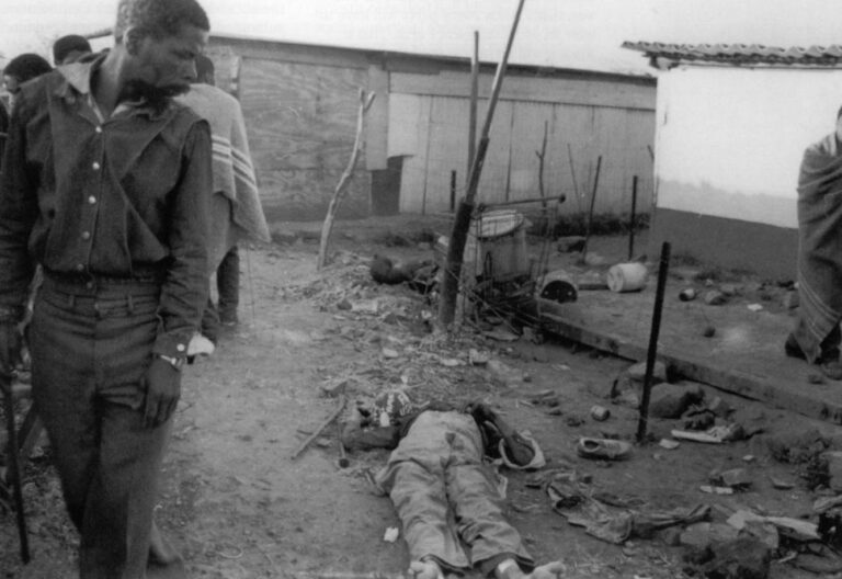 Residents walk past the body of a Zulu killed during fighting in Tokoza, South Africa in September, 1990. The bitterness among factions is challenging the Truth Commission's ability to reconcile past hatreds.