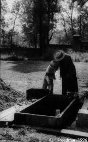 Ruth Sidonova, the rabbi's wife, teaches her son, Dany, 7, the Jewish ritual of pouring earth onto the coffin. They are at the funeral of one of the only cantors in the entire Czech Republic.