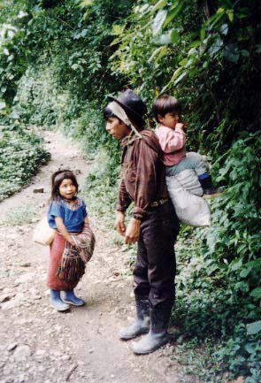 An Ixil from Caba, Guatemala carries his son and 20 pounds of luggage to Chajul for a folk holiday.