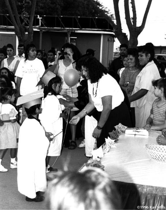 Head Start graduation at Planada migrant labor camp outside Merced, California. Young Jahdaiz Ortega (center) is congratulated as another child receives her diploma from center supervisor Anna Moreno.