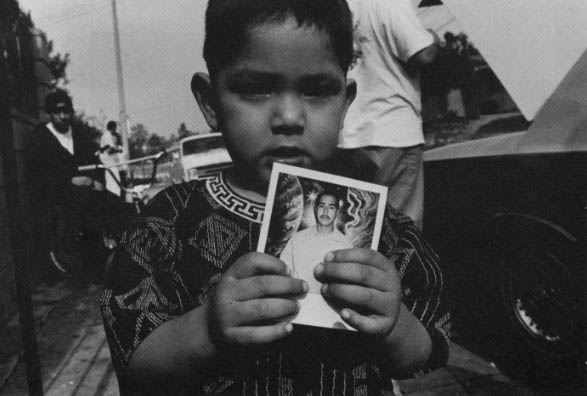 Michael, 4, holds a photograph of his father, Jimmy, who is in prison on a murder charge.