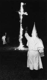 David Duke, rear, salutes a burning cross at a Klan rally in Euless, Texas in 1979, the year he said he left the KKK. Duke, a Republican, won a house seat in Louisiana by 227 votes, ran for governor and threw the state party into disarray over whether to support him or not. Photo by APF Fellow Vince Heptig.