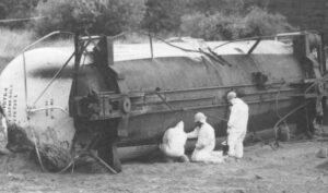 Emergency workers wearing protective gear plug a hole in the side of a railroad tanker near Dunsmore, California. The car spilled 19,000 gallons of a powerful weed killer into the Sacramento River in July of 1991 and was pulled from the river. The spill demonstrates the risks of transporting chemical weapons. AP/Wide World Photo