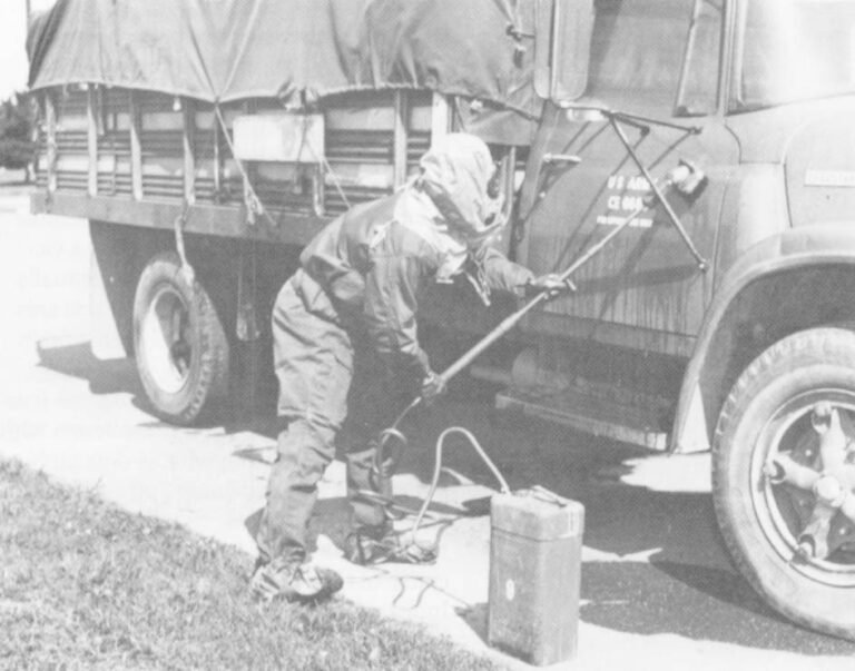 A soldier demonstrates a pump and brush designed to remove toxic contaminants from vehicles and equipment. Photo Courtesy Of The Department Of The Army.