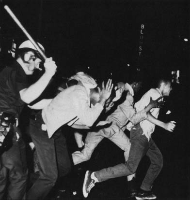 A policeman wields a club against youths on West 125th Street in New York during a night of violence in 1964. Photo by AP Wide World Photos.