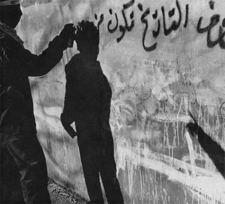 A masked Palestinian militiaman paints illegal revolutionary graffiti on the walls of Arrura in the West bank. The words translate, "The letters of history are fake unless they are written in blood\0xD0Fatah."