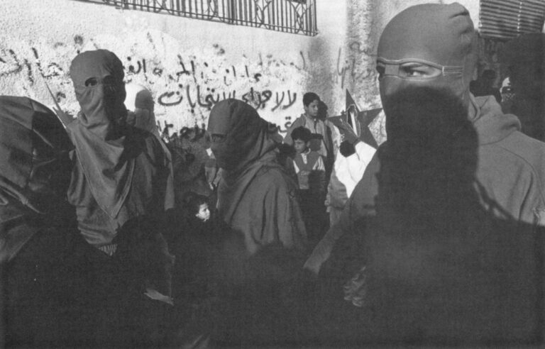 Masked and uniformed members of a Palestinian strike force celebrate the founding of the Democratic Front for the Liberation of Palestine at the Tulkarm Refugee Camp on the West Bank. About 300 marchers participated in the illegal demonstration until the Israeli army placed the camp under curfew for several days.