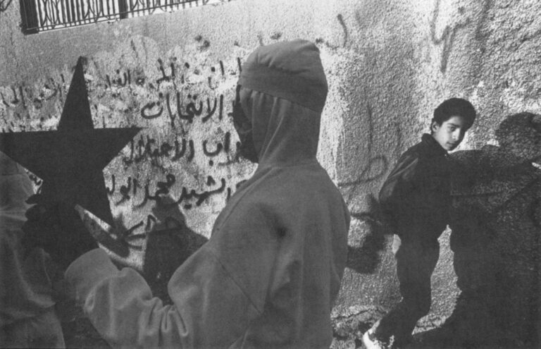 The Palestinian strike force at the Tulkarm Refugee Camp on the West Bank celebrates by a graffiti-covered wall reading, "No for the election plan! We will not bow to swords of occupation."