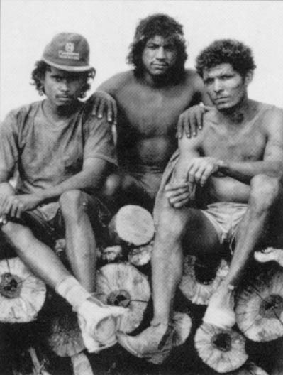 Three Brazilians, their bodies covered with charcoal dust, help load wood in the forest surrounding Acailandia. Photo By Andrew Posner ©1991