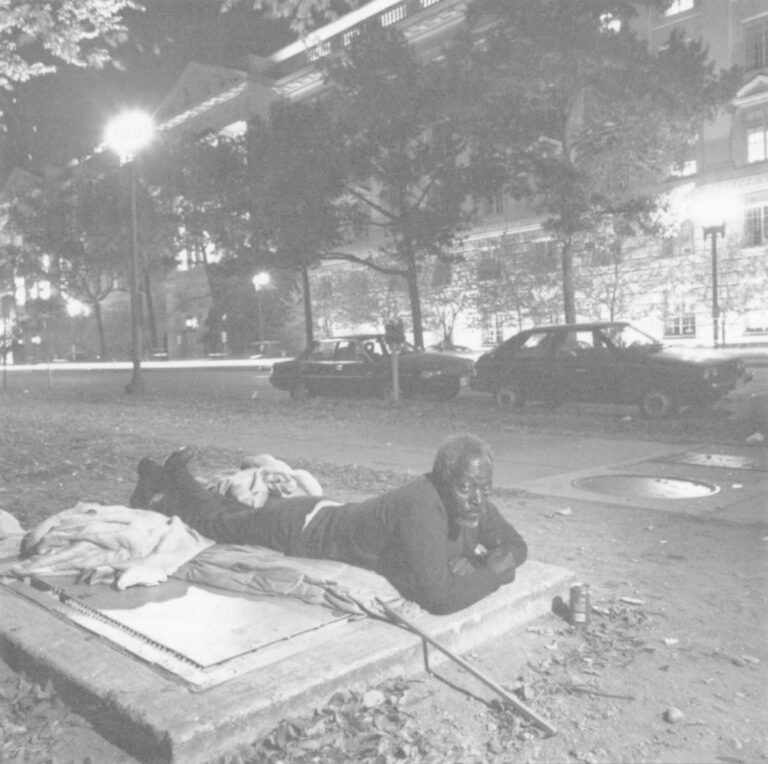 A homeless man lies on a steam grate outside a federal building in Washington, D.C. Photo by Michael O’Brien.