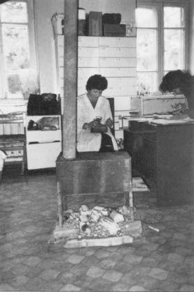 A nurse in Stepanakert’s unheated hospital sits in an intensive care ward warmed by a wood stove. Bottles of intravenous fluid are kept below the stove to keep them warm enough to use.