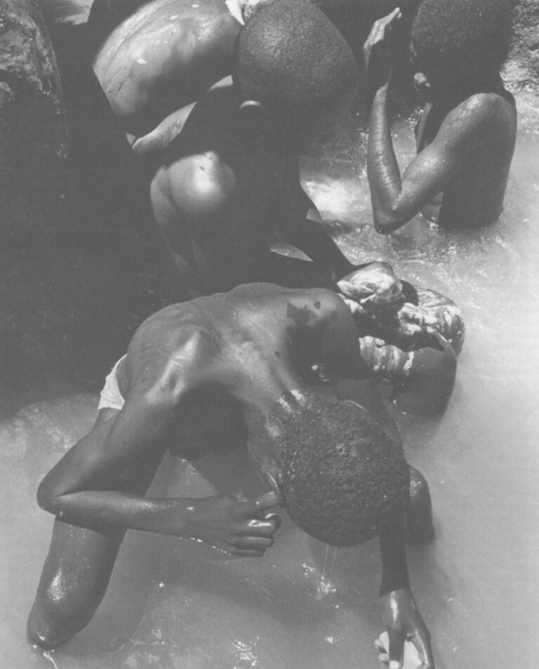 Wildek Filibert cleans his ears as he bathes with other streetboys in the Carrefour River south of the capitol building.