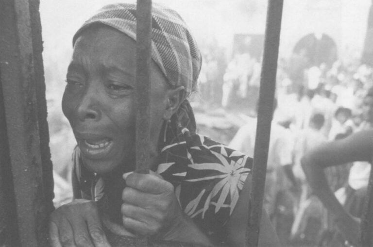 A vendor cries after her wares were burned by the TonTon Macoutes as they intimidated citizens from voting.