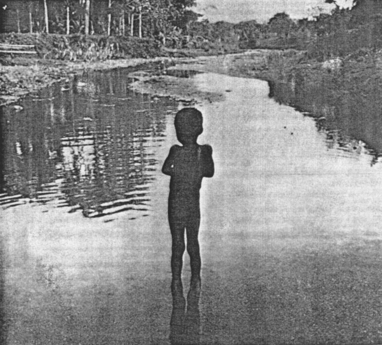 A boy stands in the shallow Duverger River in southern Haiti. The river is the village's sole source of water for bathing and drinking.