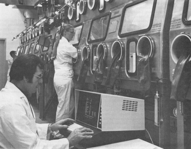 "Technicians at the Los Alamos National Laboratory must give instructions to a computer (terminal in foreground) in order to gain access to plutonium. The computer monitors the inventory and identifies discrepancies or irregularities in handling in order to provide rapid detection of possible diversion." Photo courtesy of Los Alamos National Laboratory