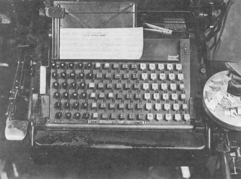 The keyboard of a Linotype-The lower case is the black section to the left, the upper case on the extreme right. In the middle are the figures, punctuation and small capitals. The spacer bands are brought down by the shiny lever just to the left of the lower case "e." The casting lever is the stump in the lower right hand corner. Scattered about on the circular tray to the right are brass mats waiting to be sent up to their home magazine.