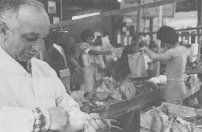 Anthony Messina has been working in Philadelphia's Italian Market for 50 years. Here, he works his produce stand with "Fonzie" in background.