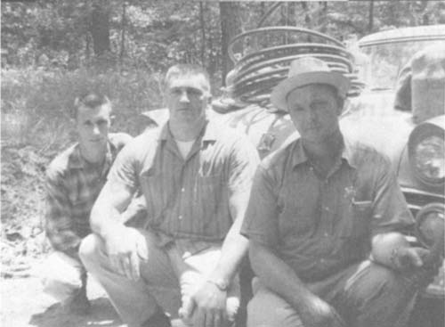 Jim Moffett (right) poses with Pusser (center) after a whiskey still raid in 1965.