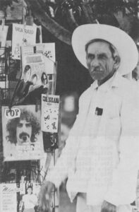 A Cuernavacan turns from a newsstand display, featuring long-haired musician Frank Zappa and "Los 3 Doors", with evident disgust. Traditions die hard.