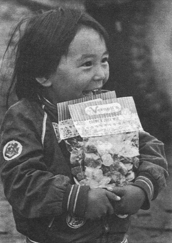 Out To Meet The Candy Man – Top, a little girl from Unalakleet, Alaska, clutches a present Moe has given her.