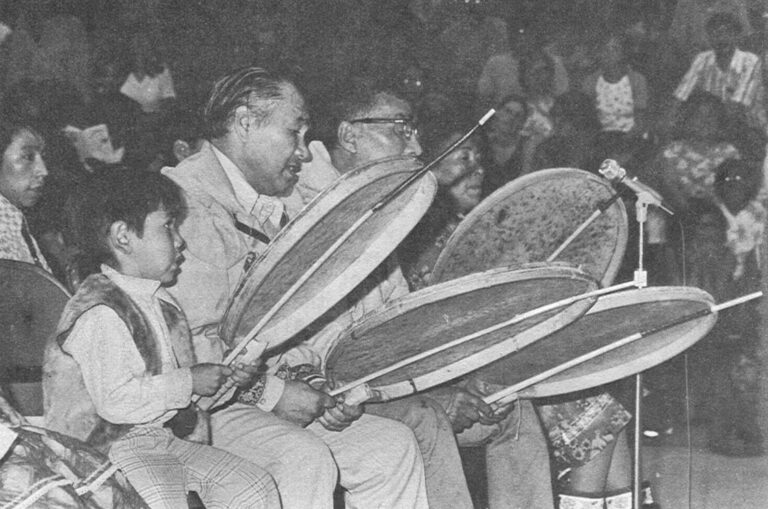 Natives Of All Ages Compete – Top a young Eskimo takes over his father's skin drum for a dance competition.