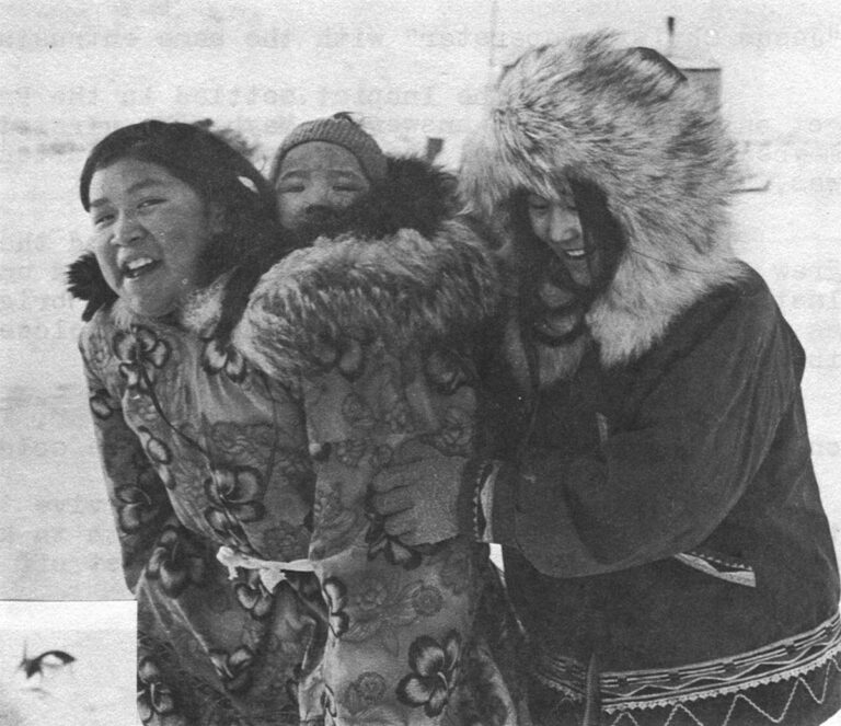The Best of the Old Ways Prevail – The girls of Anaktuvuk still prefer long, fur lined parkas and babysit the easy way, which is traditional. Directly above, Inupiat remember the old songs to the beat of skin drums.