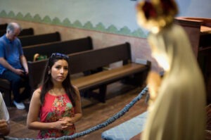 A young woman prays before a statue of Our Lady of Fatima at the Mission San Diego de Alcala. Photo by David Maung.