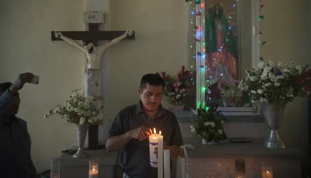 Cruz Bautista, uncle of Benjamín and patron of Holy Saviour, lights a candle in the church for the celebration.