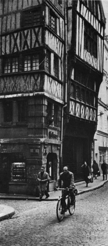 A tobacco shop and a bank have moved into old buildings. Their windows and fixtures are in fact quite new, but they don't shout it.